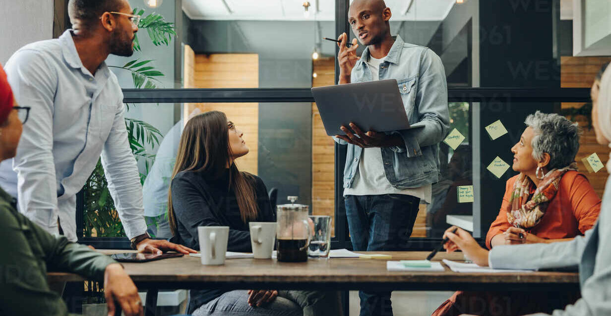 Diverse business professionals having a discussion during a meeting in a modern office. Team of multicultural businesspeople sharing creative ideas in an inclusive workplace.